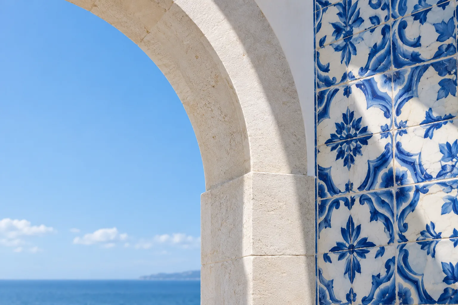 Imagem conceptual inspirada em Portugal, com um arco de pedra clara, azulejos azuis e brancos e vista para o mar.